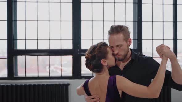 Shot of a Pair Sensually Dancing a Tango Against the Background of Large Windows