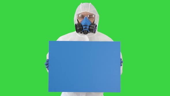 Male Doctor Wearing Protective Clothes Holding Blank Banner on a Green Screen, Chroma Key. alt