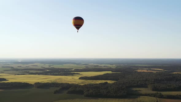 A Colored Balloon with People Flies Over Green Fields and Forests