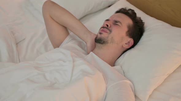 Tired Young Man Having Neck Pain in Bed alt