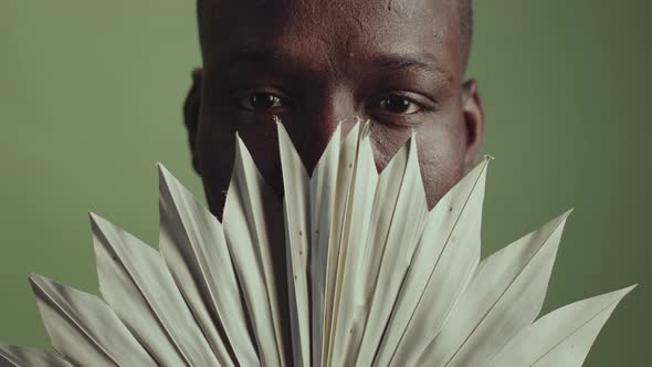 Black Man Covering Lowe Face With Leaf alt