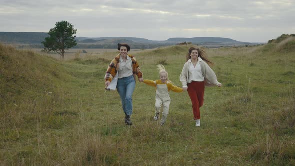 Cheerful Lgbt Family of Three Running and Smiling Outdoors alt