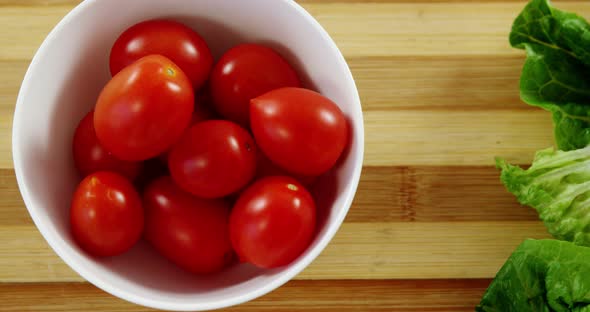 Lettuce and tomatoes in bowl on chopping board alt