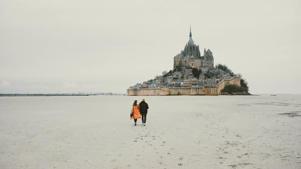 Beautiful Cinematic Shot, Drone Follows Young Happy Couple Walking Towards Mont Saint Michel alt