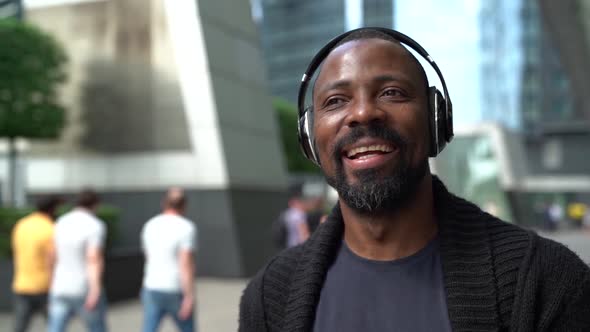 Happy African American Man Walks Through the Business Center of the City Listening To His Favorite alt