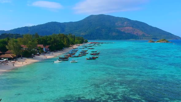 A distance but aerial shot  of boats being park with unrecognisable people by the beach. alt