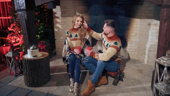 Young couple warming near fireplace in the evening. Romantic atmosphere before winter holidays. alt