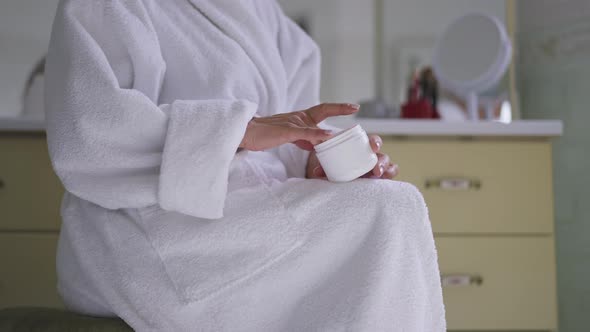 Unrecognizable Middleaged Caucasian Woman Applying Hand Cream Sitting in Bathroom at Home in the alt