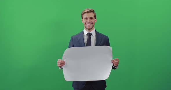 Businessman in a Suit Standing and Holds a White Poster, Template, Man Smiles and Looks at the alt