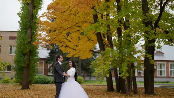 Romantic Wedding in Park in Autumn Day Bride in White and Groom in Black are Dancing Outdoors alt