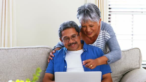 Senior couple using laptop in living room 4k alt