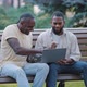 African American Black Male Friends Sitting in Park Looking at Computer Screen - VideoHive Item for Sale