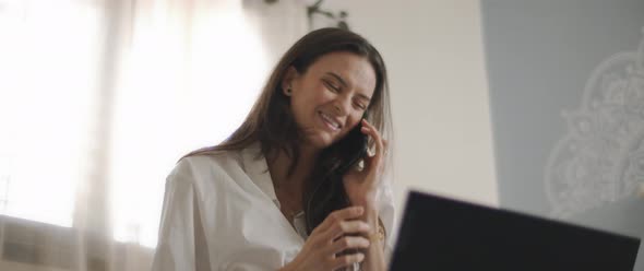 Close up of a woman in white shirt talking to someone on the phone,  alt