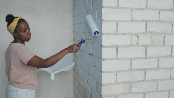 Portrait of Black Woman Painting Brick Wall alt