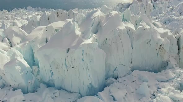 Aerial: glacier ice formation and crevasse reveal, tilt down view alt