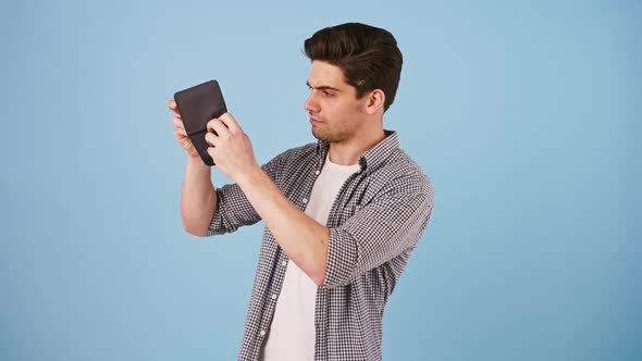 Young Male in Casual Clothes is Opening Black Wallet Which is Empty Looking Disappointed and alt