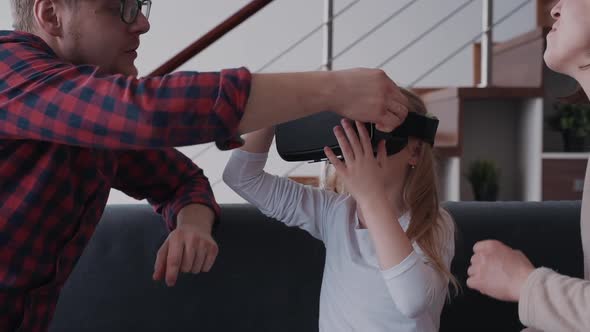 Father Helping Wearing Virtual Reality Helmet on Daughter Headt
