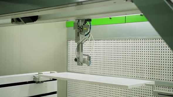 Industrial equipment for door production. Automated machine is painting wooden board in white color. alt