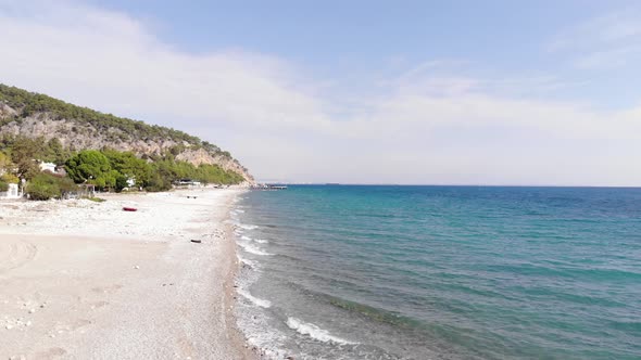 Aerial View of the Mountain Coast with Buildings Among the Trees and the Bright Blue Sea with alt