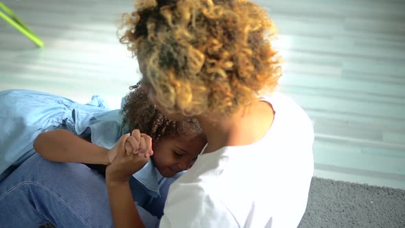 American African Woman and Little Girl Having Fun and Lying on Floor in Laundry Room at Home Spbd alt
