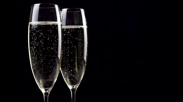 Two glasses of champagne with bubbles on black background