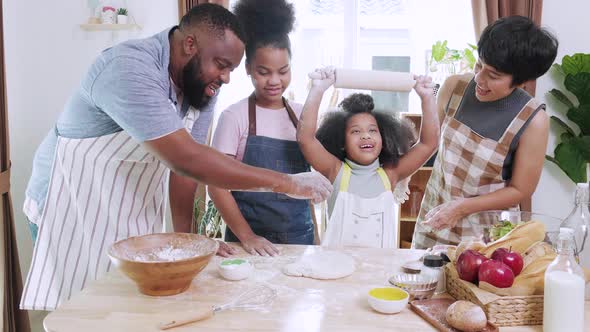 Funny African American family preparing flour to make bread in kitchen at home.