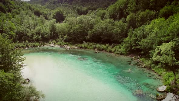 Aerial view of the Soca river surrounded by nature at summer time in Slovenia. alt