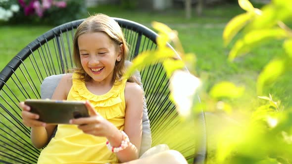 Happy kid girl playing game on mobile phone in the park outdoor