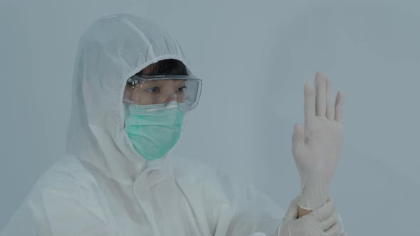 Wearing gloves. Doctor with PPE and mask wear rubber nitrile hands glove. Doc putting on gloves