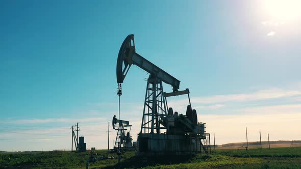 Oil Pump Is Moving While Extracting Oil Outdoors. Oil and Gas Industry Concept. alt