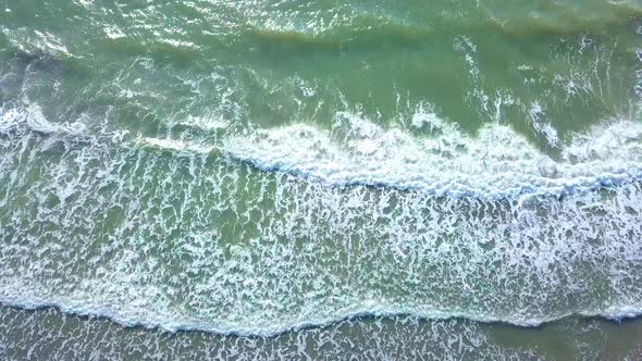 Drone view of the beautiful waves on the sandy beach, alt