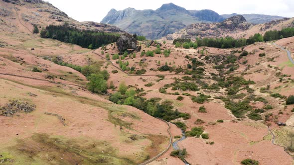 Aerial View Over Hills Towards Mountains