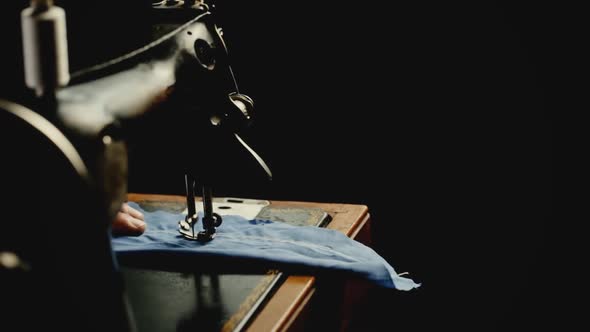 Seamstress Sews With White Thread On An Old Sewing Machine On A Black Background