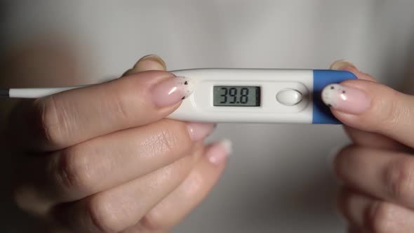 Woman Holds Thermometer in Hands to Measure Body Temperature