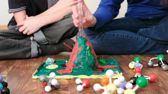 Mom and Son's Hands Make Experience with Plasticine Volcano at Home. Chemical Reaction with Gas