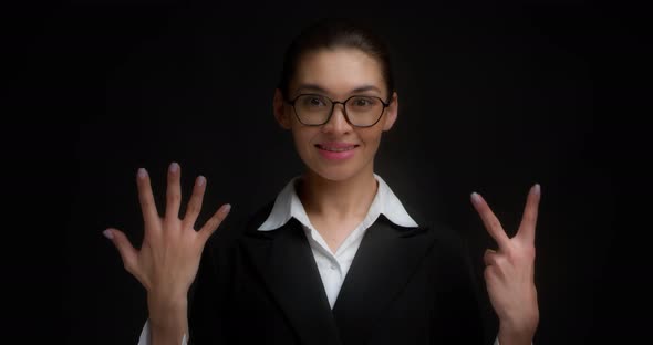 Asian Woman in Glasses Smiling and Shows Seven Fingers with Her Hand