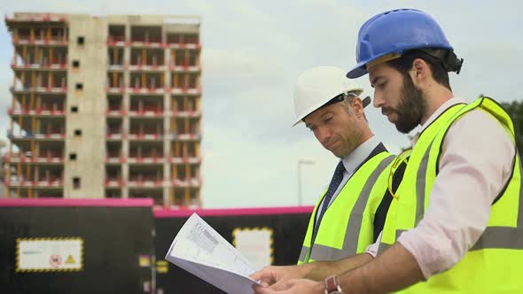 Male architect discussing with blueprint at construction site