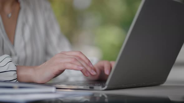 Closeup of a Woman Typing on a Laptop Keyboard While Sitting in a Summer Cafe alt