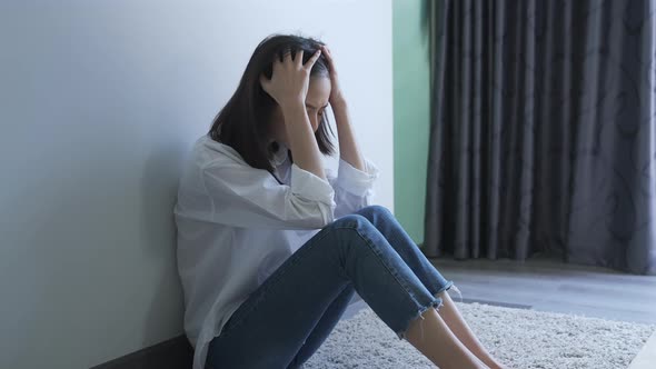 Women sitting on the wall in the room alone, show stress from life problems.