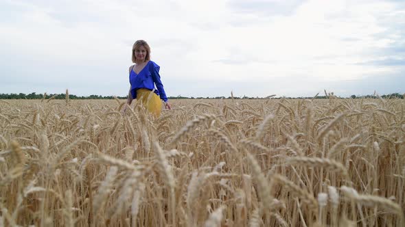 Beautiful Ukrainian Woman Wearing Dress in Ukrainian National Flag Colours Blue and Yellow at Wheat alt
