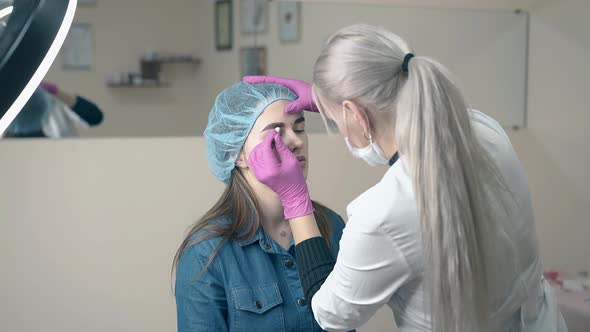 Makeup Master Makes Eyebrow Tattooing To Client in Salon alt