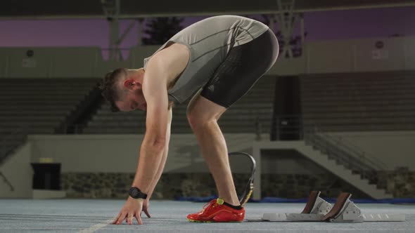 Caucasian disabled male athlete with running blade getting ready to start a run alt