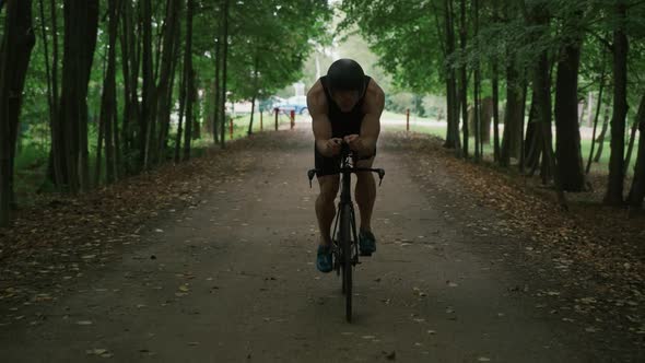 Triathlete Rides a Bike Pro Cyclist Rides on a Forest Road Preparation for Competitions and alt