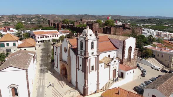 Silves Cathedral from the main portal overlooked by the Castle in the background in Algarve alt