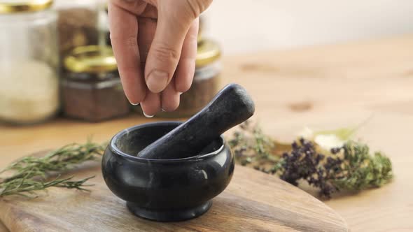 Woman's Hand Puts Herbs and Flowers Into the Granite Mortar with Pestle alt