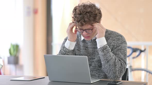 Young Man with Headache Using Laptop at Work  alt