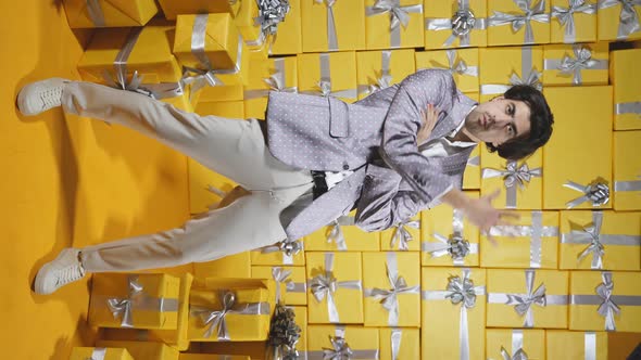 An Attractive Man in a Suit is Dancing Against the Background of Gift Boxes