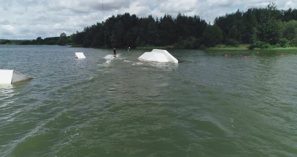 Wakeboarding, the Sportsman Surfs on the Water, Ride on a Wakeboarding Board and Performs Tricks alt