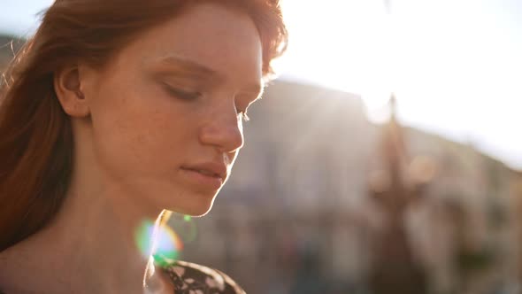 Dreamy Young Ginger Girl Looking Away Than Down and in Camera with Solar Flare in Slowmotion alt