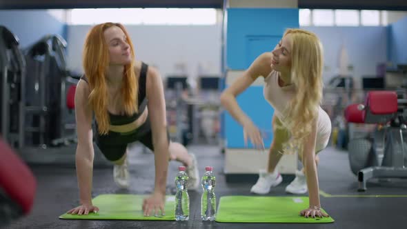 Front View of Two Cheerful Smiling Beautiful Caucasian Sportswomen Giving Highfive Standing in Plank alt
